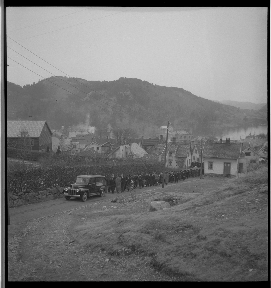 Begravelse i nærheten av Egersund. Det er bilder av kista med blomster, og av seremonien med folk som følger den døde til graven.