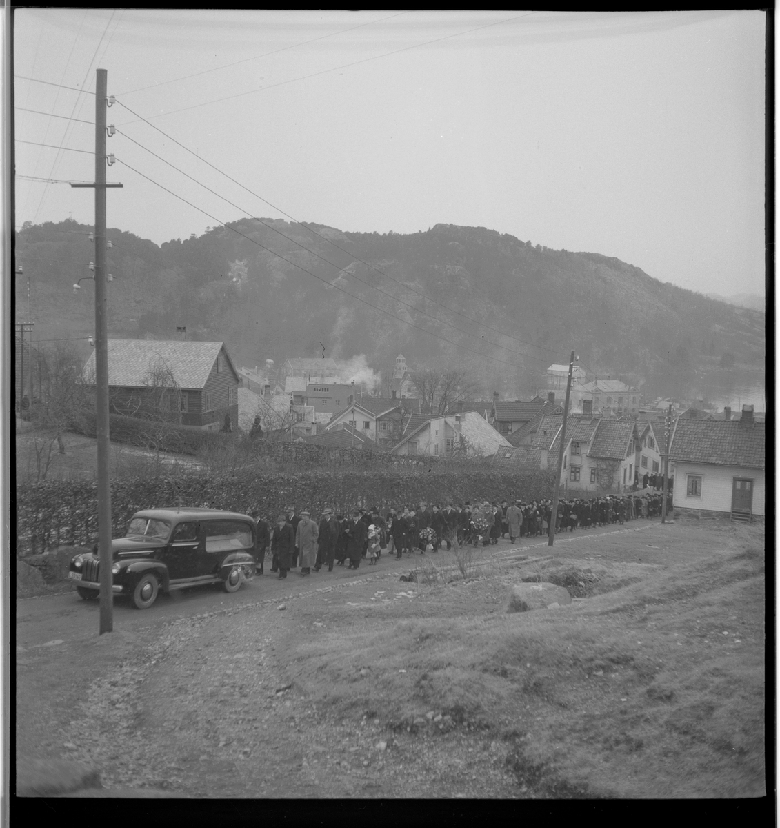 Begravelse i nærheten av Egersund. Det er bilder av kista med blomster, og av seremonien med folk som følger den døde til graven.