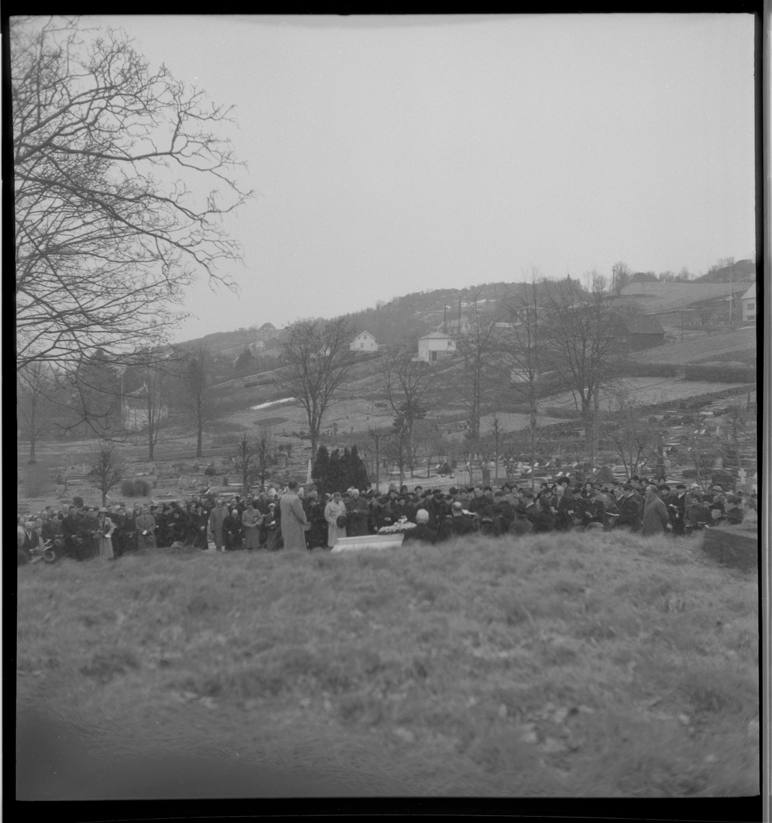 Begravelse i nærheten av Egersund. Det er bilder av kista med blomster, og av seremonien med folk som følger den døde til graven.