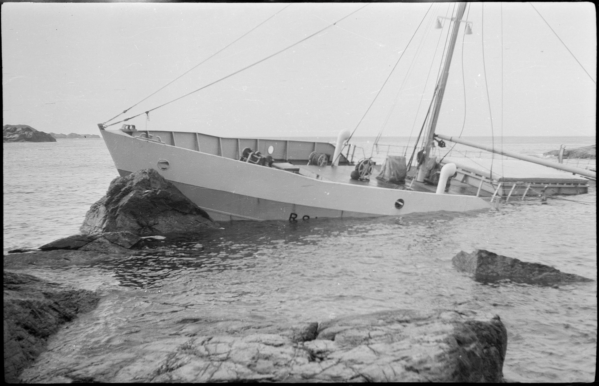 Lasteskipet "Rolfsøy" på grunn utenfor Egersund. Flere mindre båter er uten for å se og forankre skipet.