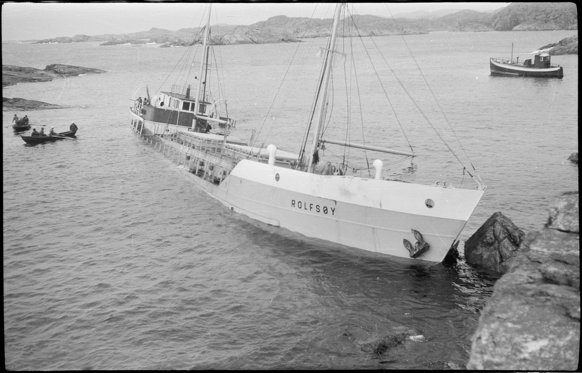 Lasteskipet "Rolfsøy" på grunn utenfor Egersund. Flere mindre båter er uten for å se og forankre skipet.