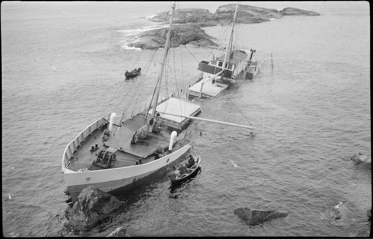 Lasteskipet "Rolfsøy" på grunn utenfor Egersund. Flere mindre båter er uten for å se og forankre skipet.