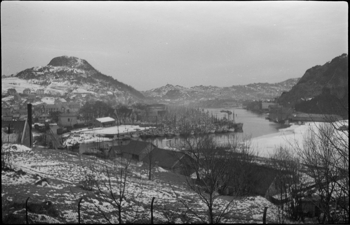 Utsikt over Vågen og Egersund en vinterdag. Det fiskeflåten ligger til kai og den innerste delen av Vågen er islagt. På bilde nr. 3 ser to menn ut over byen.