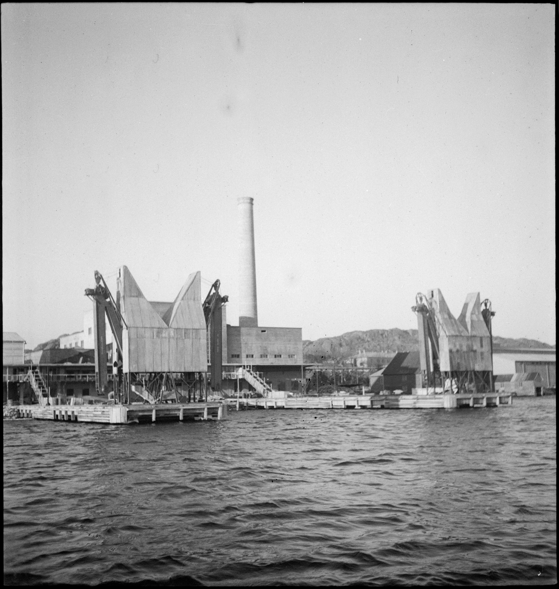 Sildoljefabrikken SILFAS på Grønehaugen i Eigersund rundt ferdigstillelse. Det er bilder av fabrikken, sildekummene og produksjonslinjene, samt en maskin.