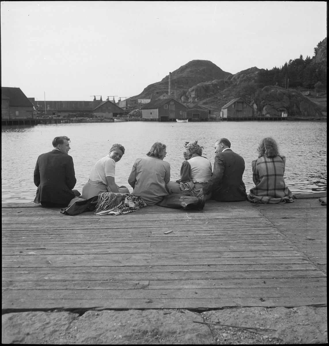 En vennegjeng er samlet for å feire Sankthans i Egersund. De er på båttur og sitter på en brygge vendt mot Lindøya.