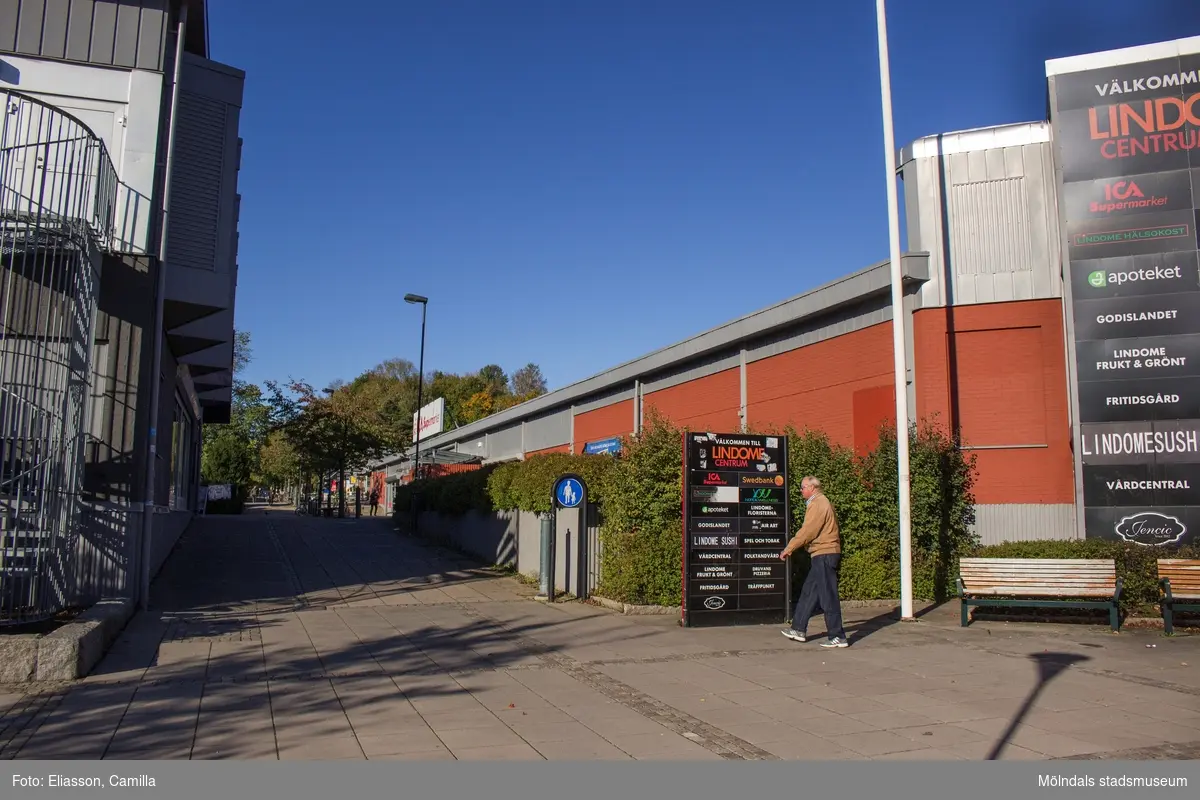 Almåsgången, sträckning västerut, i Lindome centrum den 4 oktober 2016. Till vänster ses huset Almåsgången 1 samt till höger nr 2, som inrymmer ICA Supermarket.