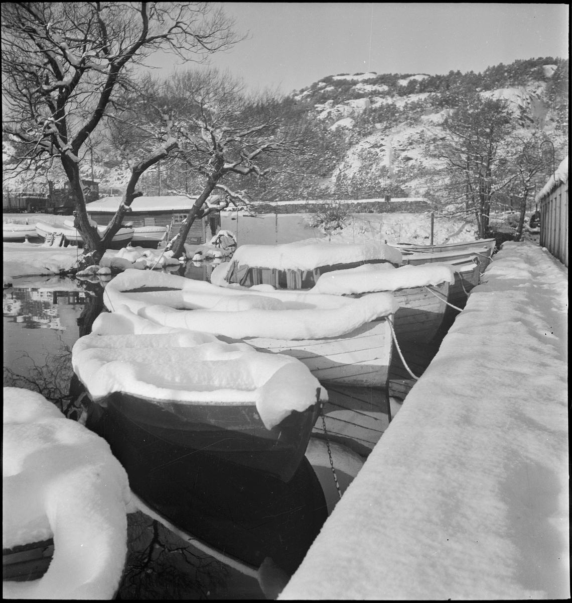 Julehilsen fra Fotohuset A/S i Egersund. Småbåter er dekket med snø i ved båthuset i Lervika