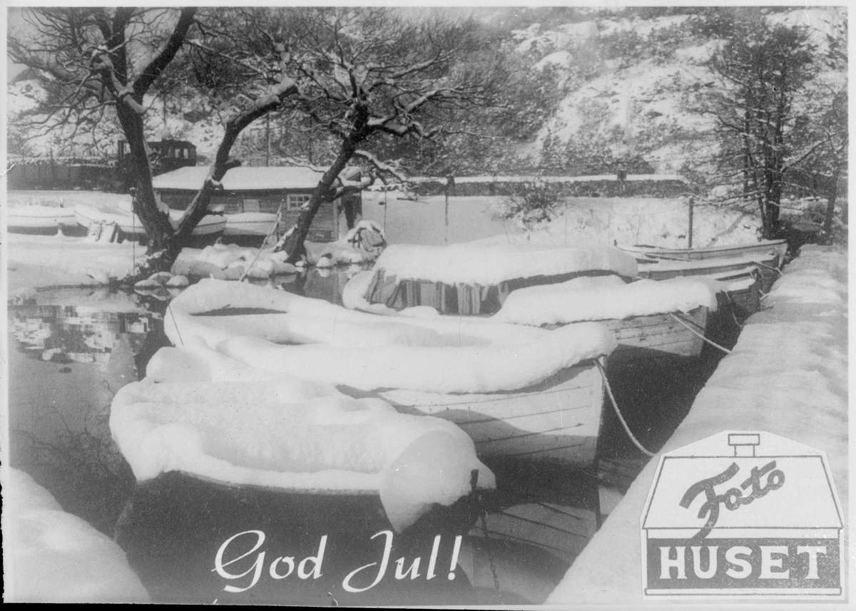 Julehilsen fra Fotohuset A/S i Egersund. Småbåter er dekket med snø i ved båthuset i Lervika