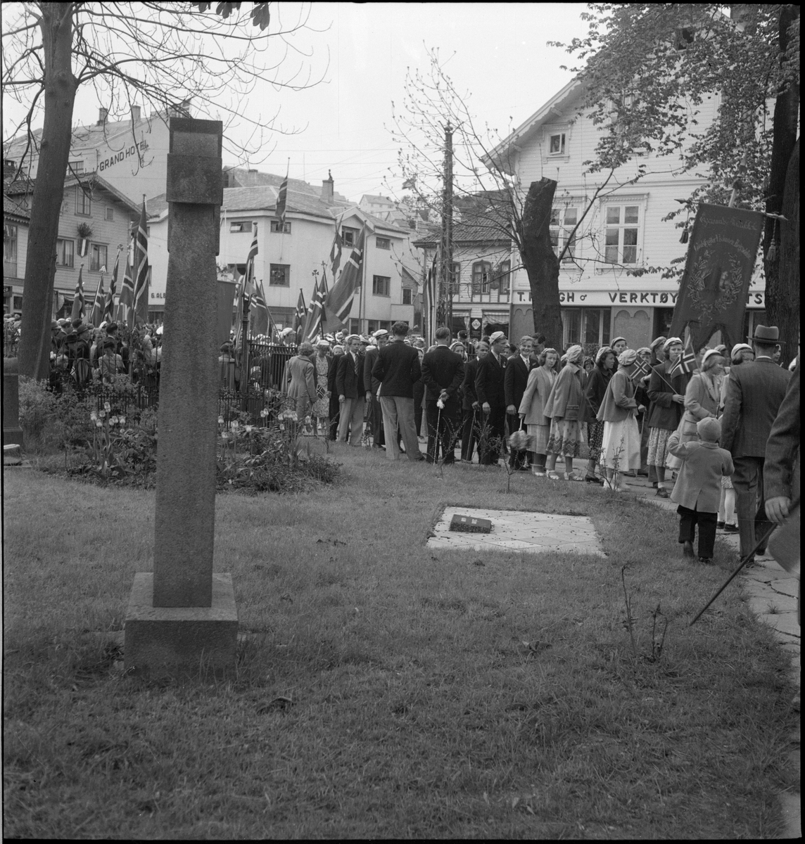 Folketog på 17. mai. Flere korps og barn går langs Vågen og igjennom sentrum av Egersund. Mange har kommet for å se toget.