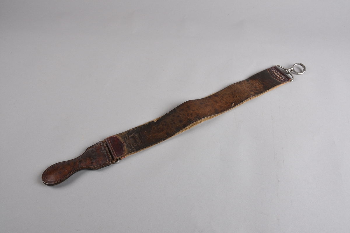 Slipereim for barberkniv. Avlang lérreim med tilsvarande stykke i grov kanvas på baksida, sydd til oppe og nede på lérreima. I endane oppe og nede påsydde endestykker i dobbelt lér. Nede er eit lérhandtak festa med bøyel i endestykket. I endestykket oppe er det festa ein metall opphengskrok med bøyel. Sjølve kroken er todelt og kan klemmast saman til ein sirkel for oppheng.