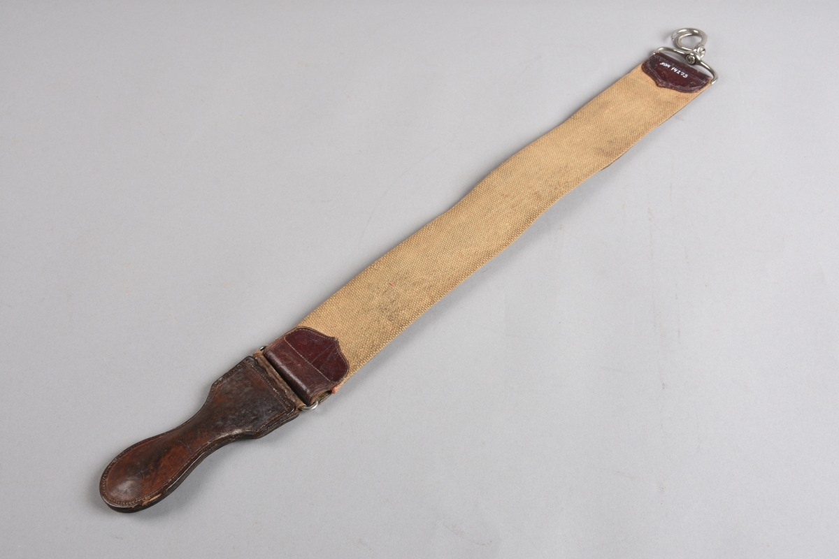 Slipereim for barberkniv. Avlang lérreim med tilsvarande stykke i grov kanvas på baksida, sydd til oppe og nede på lérreima. I endane oppe og nede påsydde endestykker i dobbelt lér. Nede er eit lérhandtak festa med bøyel i endestykket. I endestykket oppe er det festa ein metall opphengskrok med bøyel. Sjølve kroken er todelt og kan klemmast saman til ein sirkel for oppheng.