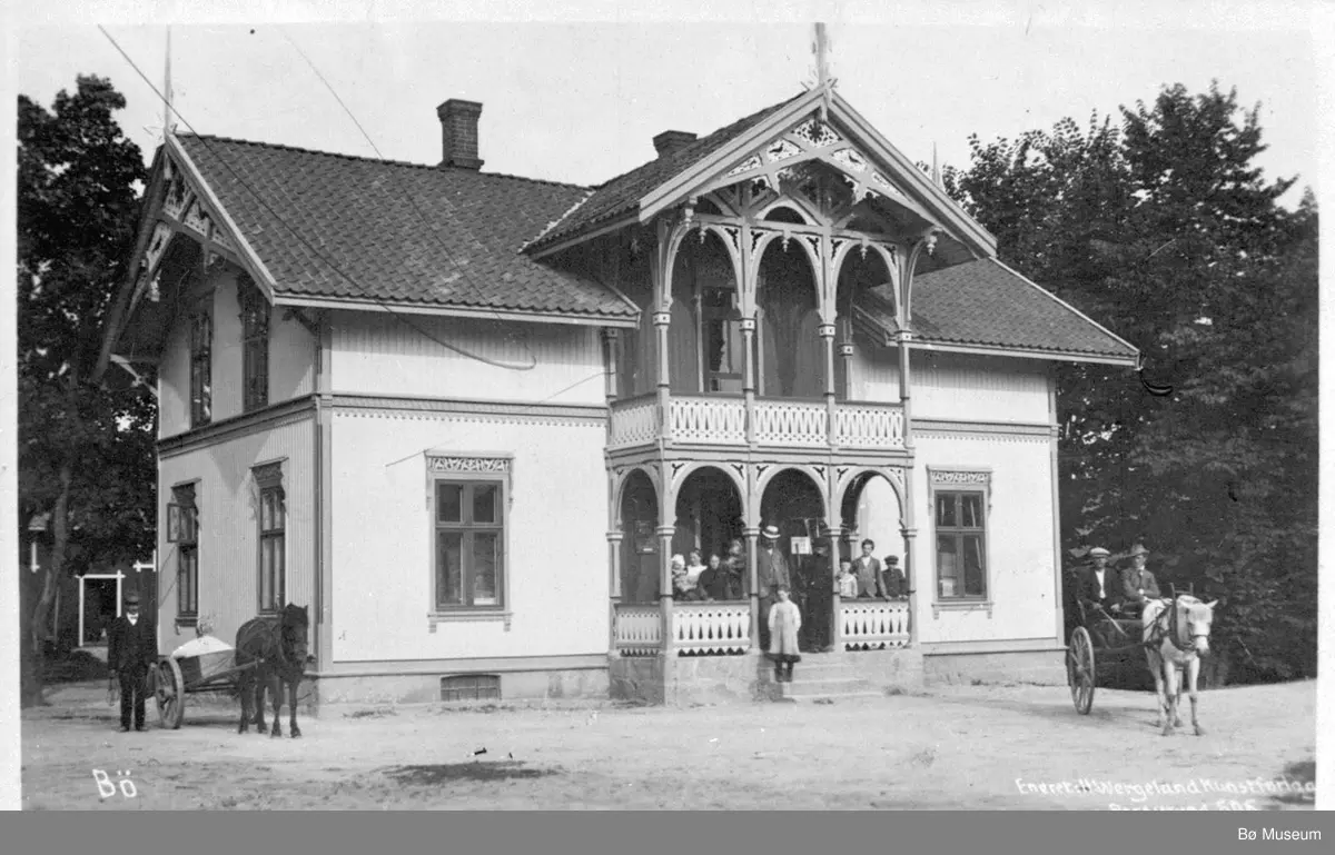 Åheim landhandel på Oterholt i Bø (nåv. Bø Museum) fotografert med folk og hestar framfor.