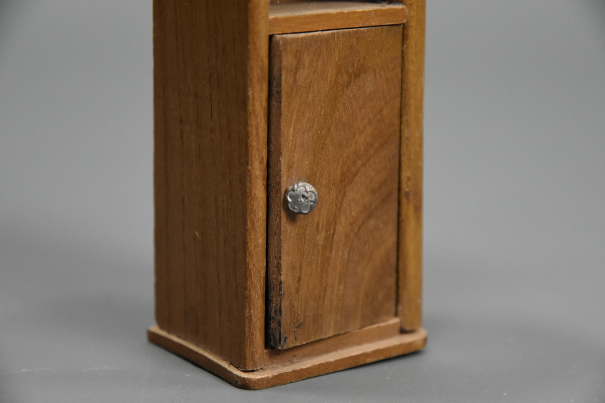 Vaskevannstol i toalettmøblement til dokkemøblement i treverk med steinplate. Plata er skadet. Dokkemøbler ble gitt til jenter til lek som forberedelse til voksenlivet.  