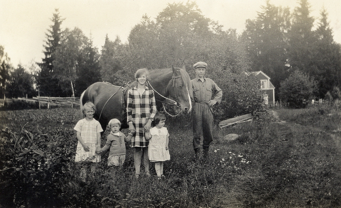 En tonårspojke och en tonårsflicka tillsammans med några barn och en häst vid ett trädgårdsland.