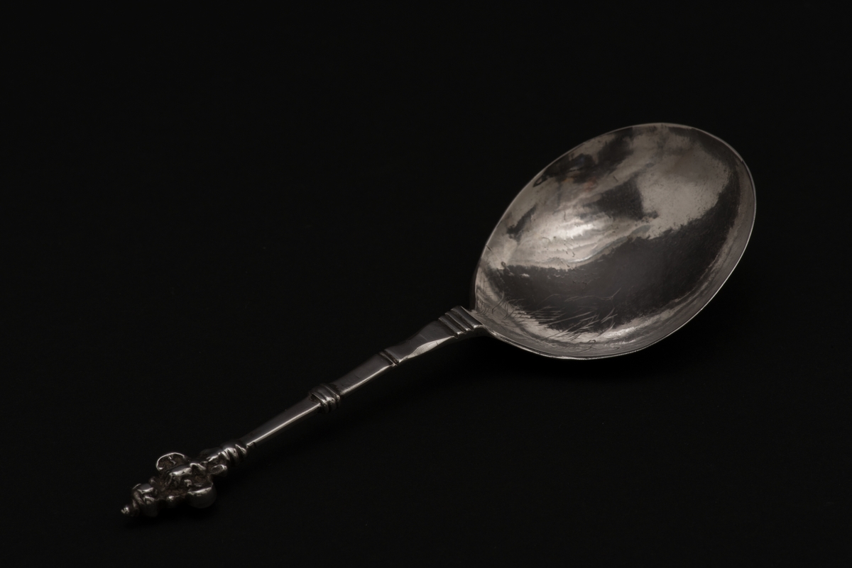 Supsked av silver med runt blad och profilerat skaft.
Skaftet avslutas med en dubbel kerubknopp, med ett stiliserat kerubansikte. Bladet är graverat med bladornament.
Stämplarna visar att skeden är tillverkad av Henrik Reimers, Norrköping.