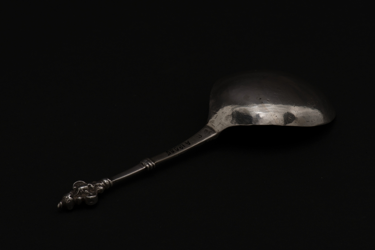 Supsked av silver med runt blad och profilerat skaft.
Skaftet avslutas med en dubbel kerubknopp, med ett stiliserat kerubansikte. Bladet är graverat med bladornament.
Stämplarna visar att skeden är tillverkad av Henrik Reimers, Norrköping.