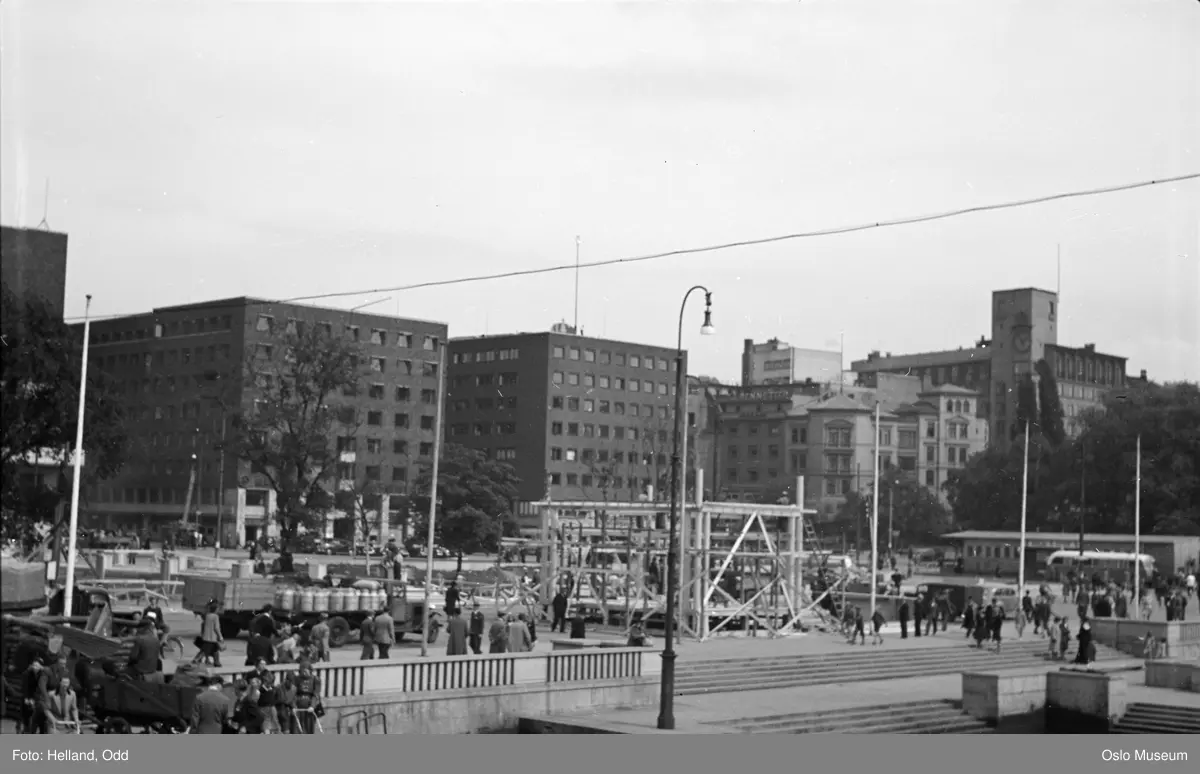 Rådhusplassen klargjøres til kongens hjemkomst, bygging av paviljong, mennesker, biler, kontorbygninger