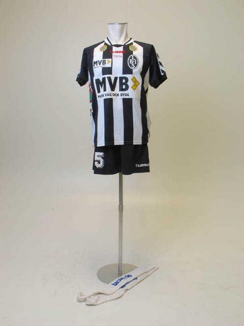 Matchdress från Landskrona BoIS. Använd av Johan Andersson, nummer 25, 2006. För hemmamatcher; svarta shorts, vita strumpor och kortärmad matchtröja. Reklamtryck på alla plaggen.
Mått: Strumpor: L 67 cm
Tröja: B 51, L 70 cm
Shorts: H 43, B 65 cm