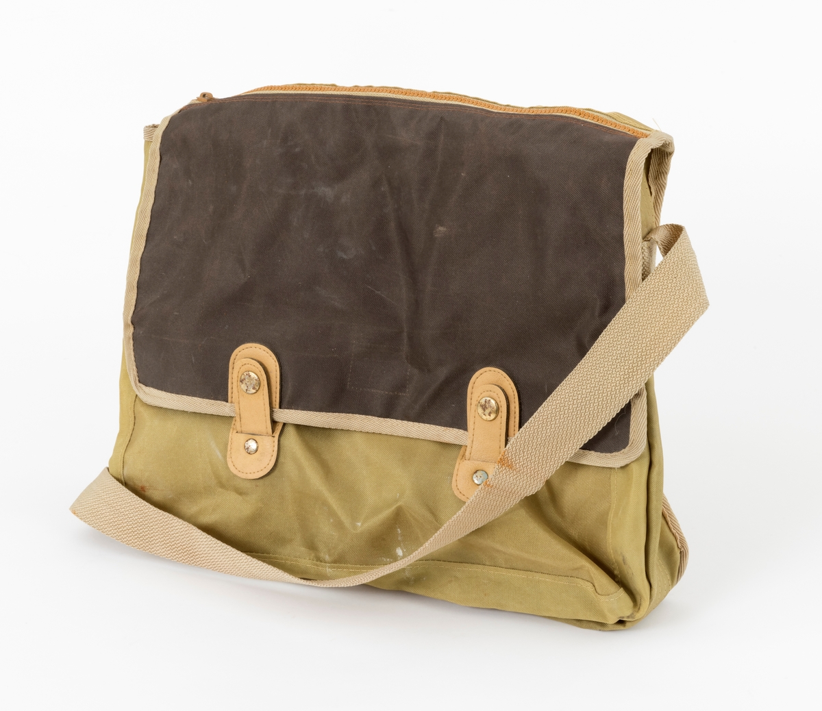 Veske med skulderreim brukt til å oppbevare utstyr under fiske. Veska er ei klaffeveske laget i grønt og brunt nylonstoff med detaljer i lyst kunstklær og metall. Den er kantet med beige bånd, samme farge som skulderreima. Veska består av et stort rom, i tillegg til to lommer, ei ytterlomme og ei lomme på utsiden av klaffen. Veska lukkes med to tykknapper. Lommene lukkes med glidelås.