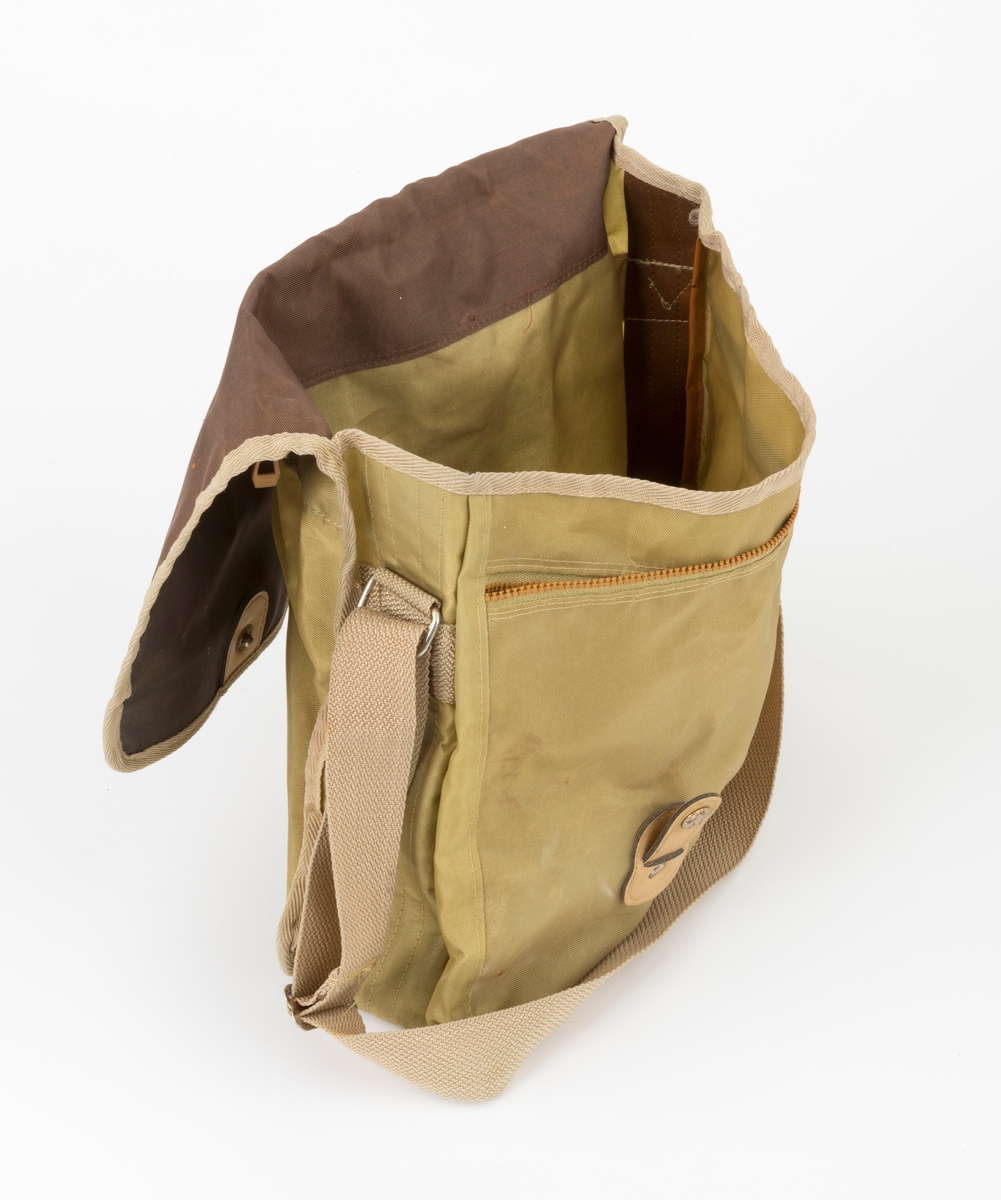 Veske med skulderreim brukt til å oppbevare utstyr under fiske. Veska er ei klaffeveske laget i grønt og brunt nylonstoff med detaljer i lyst kunstklær og metall. Den er kantet med beige bånd, samme farge som skulderreima. Veska består av et stort rom, i tillegg til to lommer, ei ytterlomme og ei lomme på utsiden av klaffen. Veska lukkes med to tykknapper. Lommene lukkes med glidelås.