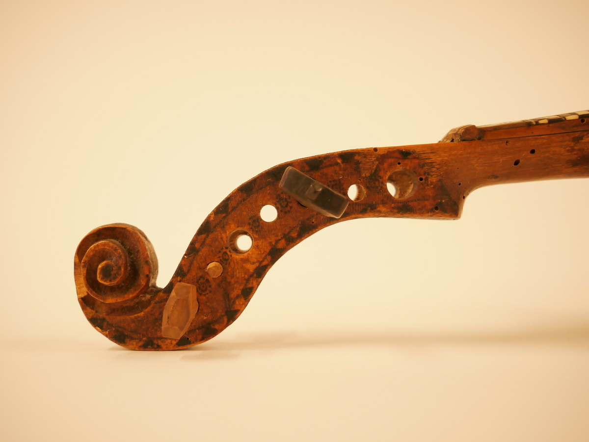 Hardangerfele. Gripebrett med dekor i tre og bein. Rikt dekorert. 
Overflatebehandla med lakk og tusj. Fint avpussa. 
Fela ligg oppi ei felekasse som truleg ikkje høyrar til. 
Lapp med tekst og årstal påskrive limt på innsida av fela.