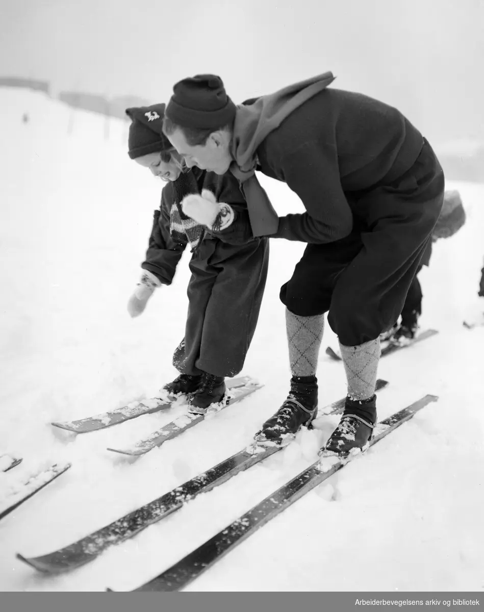 Framfylkingen. Oslo Framkrets' skiskole i Torshovdalen 13 til 17 januar 1950. Karin Mette får hjelp av instruktør Odd Ingebretsen.