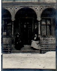 To menn og to kvinner sitjande ute på ein veranda i sveitserstil
Tatt i februar 1912