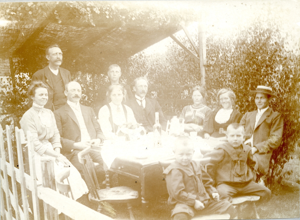 Familieselskap i lysthuset på Krossvegen i Bø.  F.v Anna Sagen, sarpsborg, Hans Sisjord ståande, Halvor H. Sagen f. 1874 d. 1955, Sarpsborg, Kari O. Saga f. 1889 d.1976, Olav H. Saga f. 1876 d. 1963, Johannes Saga ståande bak, f. 1897 d. 1981, Mari H. Saga f. 1882 d. 1973, Ronnaug Saga f. 1888 d. 1976, Kittil H. Sagen. Sitjande framme f. v Erik K. Sagen f. 1907 og Håkon K. Sagen f. 1905, begge Sarpsborg.