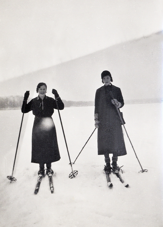 Två unga kvinnor på skidor, ute på sjöis.