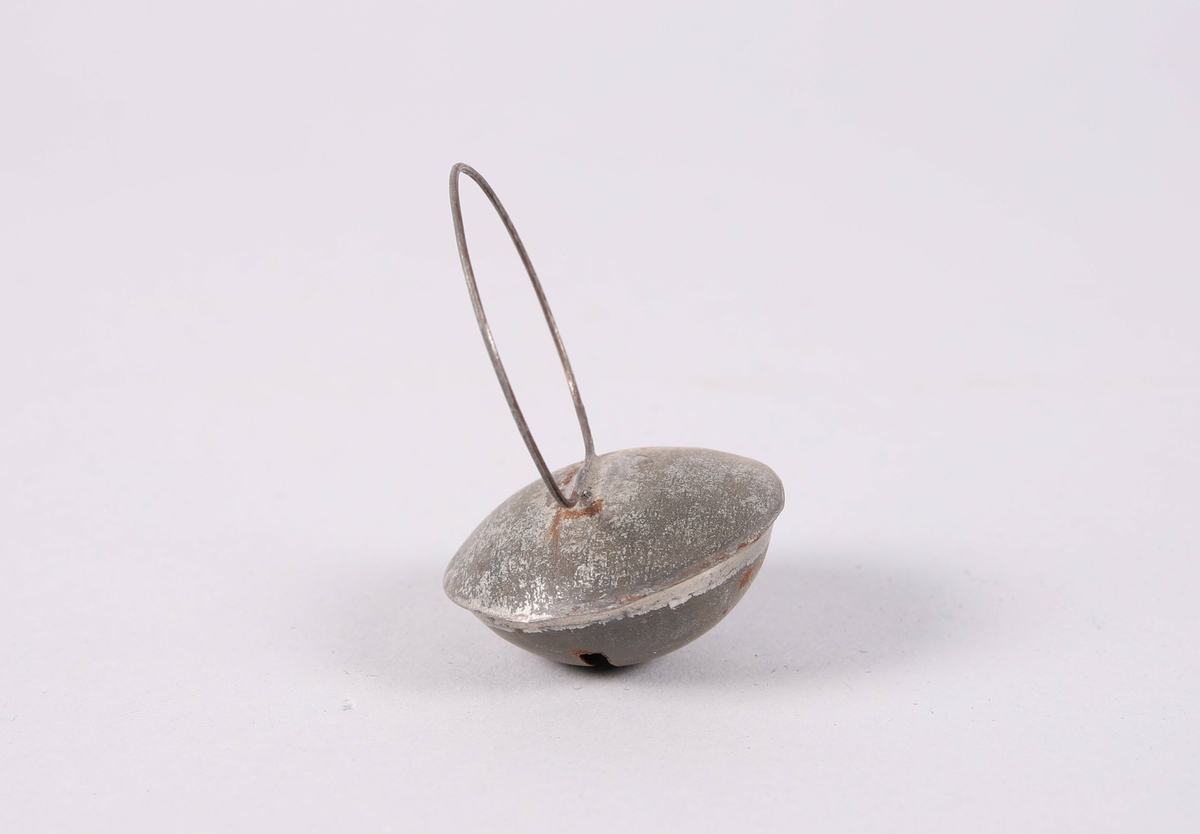 Liten bjelle for husdyr (hund eller katt). Flat dombjelle av metall med smal, rektangulær åpning. En tynn ring er festet til bjellen.

