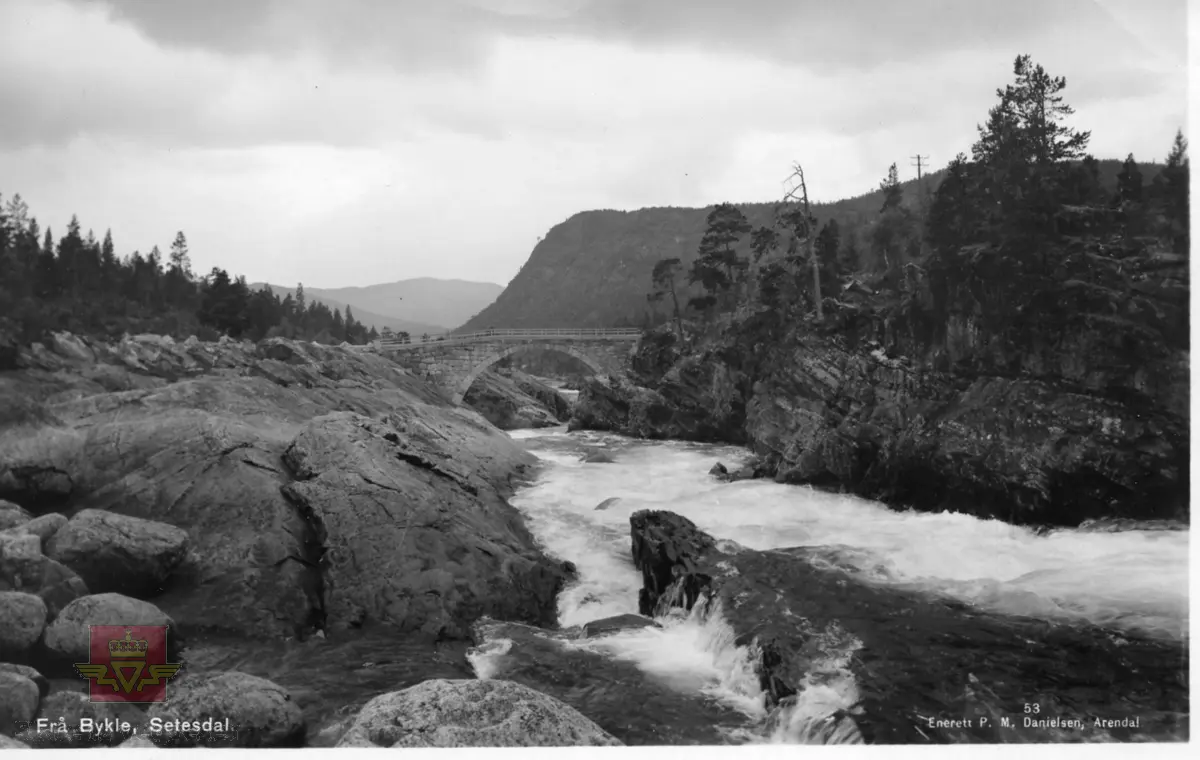 Gamle Berdal bru, Bykle. Steinhvelvbru oppført 1907, sprengt 1940. 
Postkort utgitt av P.M. Danielsen, Arendal. 
Påskrift på postkortet: Frå Bykle, Setesdal. 53 Enerett P. M. Danielsen, Arendal.