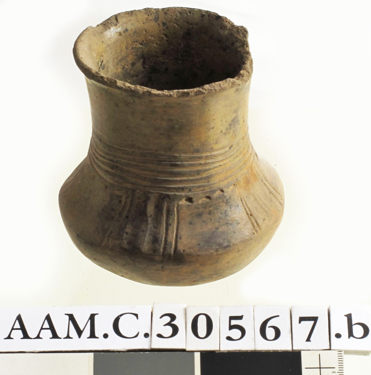 Leirkar av lyst brunlig, forholdsvis tykt, godt brent gods med glattet overflate av form som Bøe: anf. arb. fig. 157, men med noe kortere hals. Orneringen, som begynner midt på denne, består av 4-6 rekker horisontale linjebunter, som er innrisset nokså skjødesløst. Herunder - på skulderen - 4 felt med vertikale hulkiler og linjebunter anbrakt parvis. Mellom disse finnes glatte partier i hvis øvre kant det løper en punktrekke. Buken uornert, bunnen oppdrevet og avgrenset med en punktrekke. Noen skall mangler langs randen, eller utmerket bevart. Høyde 10,7 cm, munningsdiam. 8 cm, bukvidde 10,1 cm. (A. 321.) 
