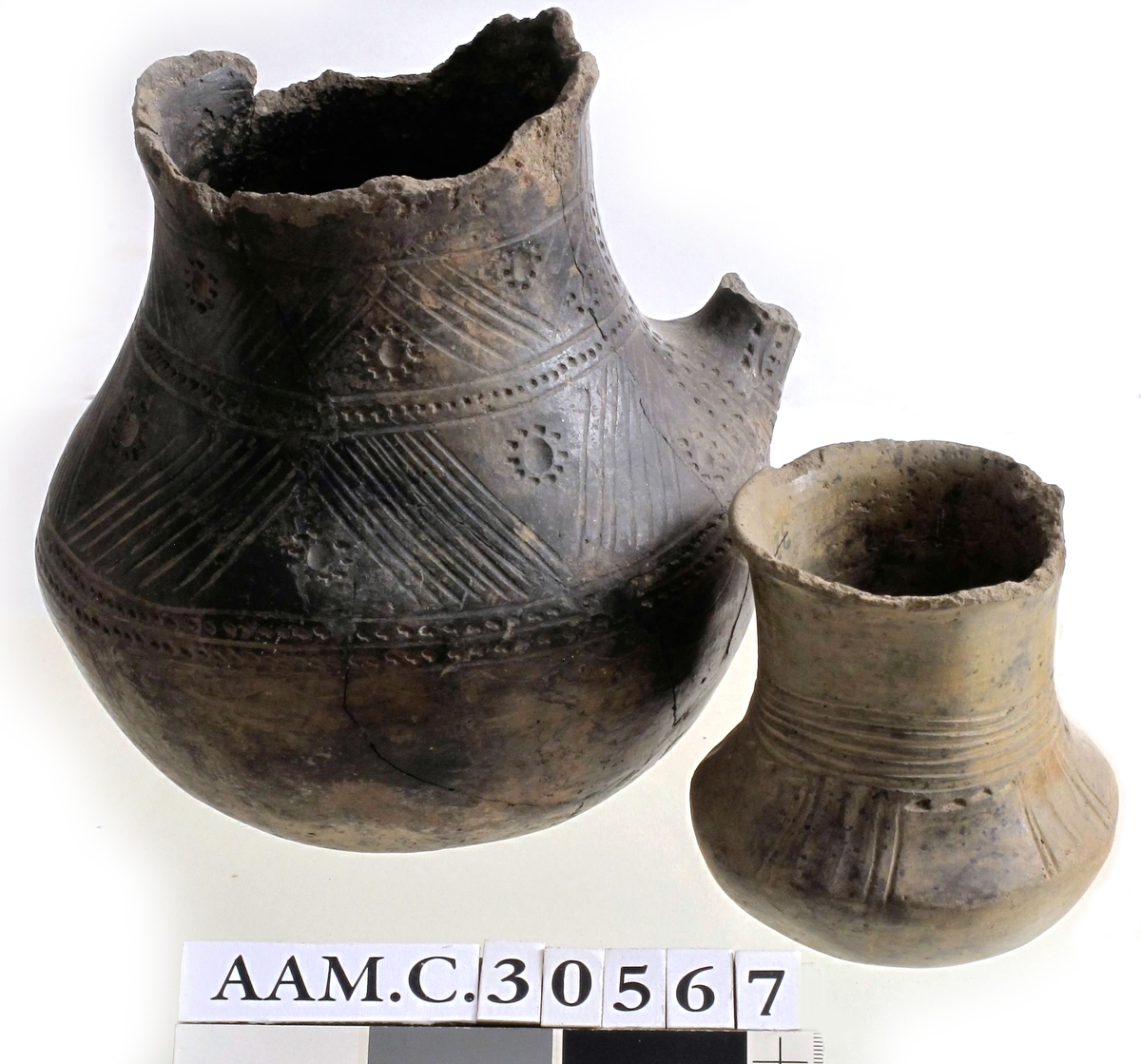 Leirkar av lyst brunlig, forholdsvis tykt, godt brent gods med glattet overflate av form som Bøe: anf. arb. fig. 157, men med noe kortere hals. Orneringen, som begynner midt på denne, består av 4-6 rekker horisontale linjebunter, som er innrisset nokså skjødesløst. Herunder - på skulderen - 4 felt med vertikale hulkiler og linjebunter anbrakt parvis. Mellom disse finnes glatte partier i hvis øvre kant det løper en punktrekke. Buken uornert, bunnen oppdrevet og avgrenset med en punktrekke. Noen skall mangler langs randen, eller utmerket bevart. Høyde 10,7 cm, munningsdiam. 8 cm, bukvidde 10,1 cm. (A. 321.) 
