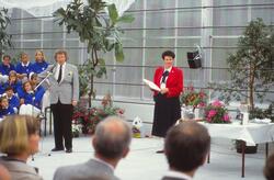 Mann som held tale, veksthus, blomar