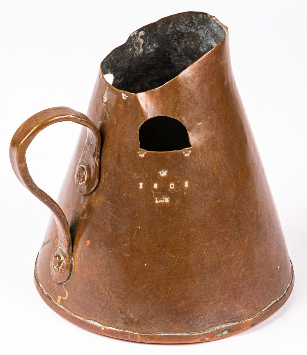 Brännvinsmått av koppar, konisk form, ett handtag. En bit bortklippt invid kröningen. Krönt 1808, LCK.