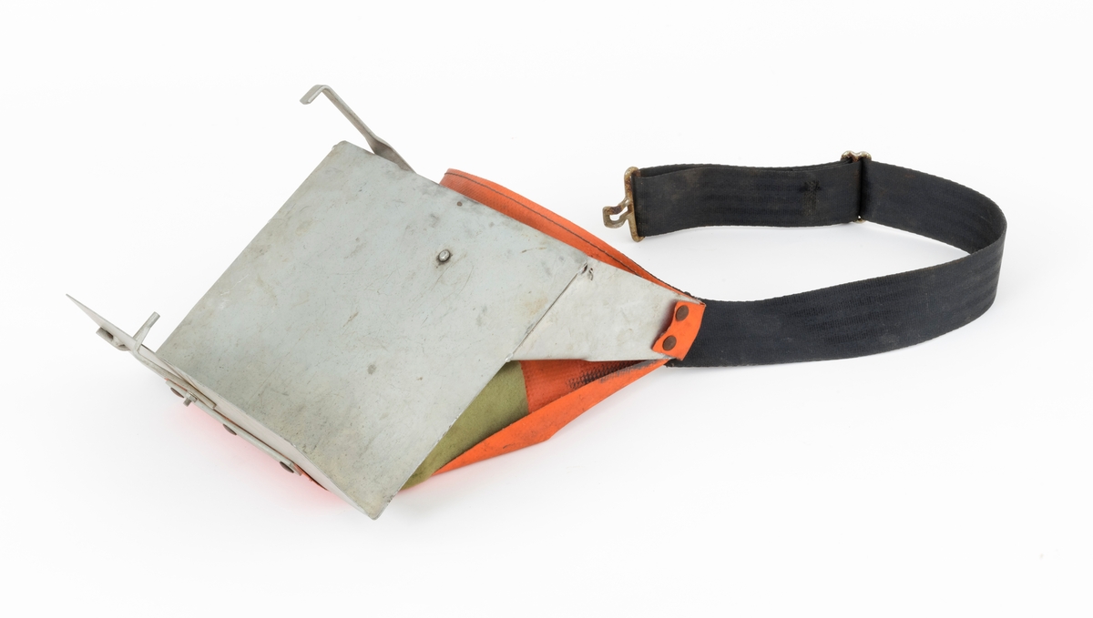 Hoftebelte med festebrakett for pottebrett med pluggrotplanter som skulle brukes til å etablere nye skogbestand. Pottebrettene ble festet vertikalt, på ei vinklert lettmetallplate som er 25 centimeter bred og snaut 20 centimeter høy. "Hylla" nederst på denne plata er 8,2 centimeter bred. For å få et standard pottebrett, som måler 40 X 30 centimeter, til å sitte fast på denne braketten, er det montert bøyler med vinklete endeledd, både på undersida av "hylla" og på baksida av den noe større plata. Den sistnevnte er fjærbelastet. Ytterst på overkantene av den store plata er det påsveiset litt skråstilte, om lag 15 centimeter lange stag, også de av samme type metallplate. I ytterendene av disse stagene er det festet et oransjefarget, gummiert lerretsstykke som delvis omslutter en lysegrønn skumgummitbit. Lerretet skulle ligge an mot hofa til brukeren, og skumgummibiten skulle tjene som pute og hindre gnag. I den øvre enden av lerretsbiten er det påsydd og fastnaglet et 4,7 centimeter bredt tettvevd belte av svartfarget syntetisk materiale. Dette beltet skal føres rundt plantørens hofter og festes med et endebeslag i en krok i det ene staget på braketten. Lengden på beltet er justerbar, slik at hoftebeltet kunne brukes av skogkulturaktører med ulik livvidde.