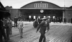 En traktor drar upp Charles Lindberghs flygplan på en slip vid dennes besök på F 2 Karlskrona flygstation på Stumholmen i september 1933. Folksamling i rörelse.