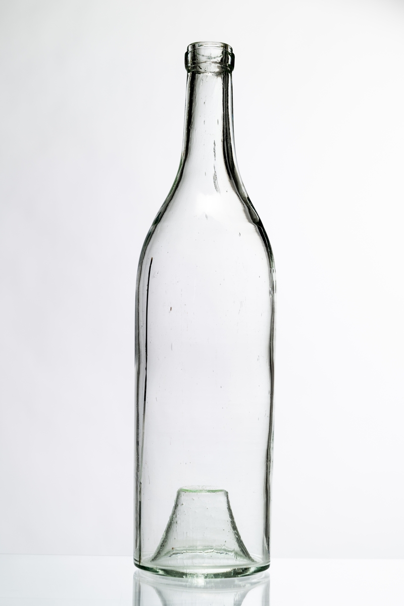 Butelj av ofärgat klart glas, avsedd för tillslutning med naturkork. Buteljen har "Kinnekullebotten". Buteljen tillverkades för klart okryddat brännvin. Klart glas användes för att innehållets äkta färg inte skulle missfärgas av glasets färg (estetisk funktion). Glaset har en drygt 18 cm lång lodrät spricka. Hantverksmässigt tillverkad vid Sunds glasbruk, Jönköpings län. Se vidare Historik.