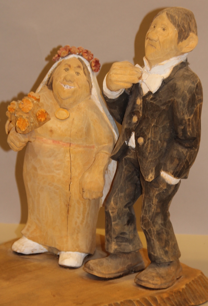 Skulptur som syner Arne Aas som tek bilete av eit brudepar. Skulpturen er skoren i tre.Tekst under:"Bjarne Walle fra Bamle laget denne gruppa på bestilling i fra fotografen Arne Aas i 1984" "Motiv: Arne Aas fotograferer brudepar". Bokstavane BW skore inn under skulpturen.