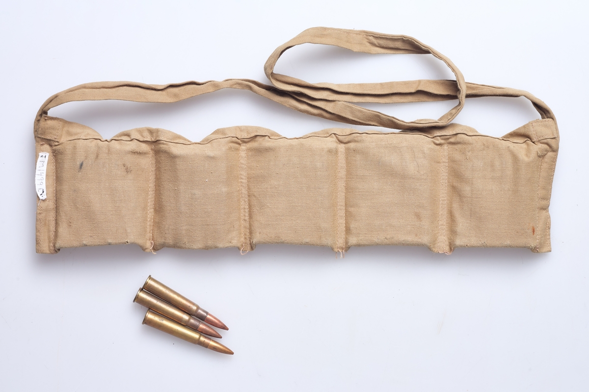 Beltet er rektangulært, laget av bomullstoff og har rom for patroner og rem for å ha rundt livet, eller over skuldra. Skarpladde patroner med helmantelkule. Beltet er oppdelt i 5 rom med klaff over, og en hekte i kobbertråd for hvert rom. Beltet inneholder ca. 50 stk. kragepatroner i kal. 303, helmantel.