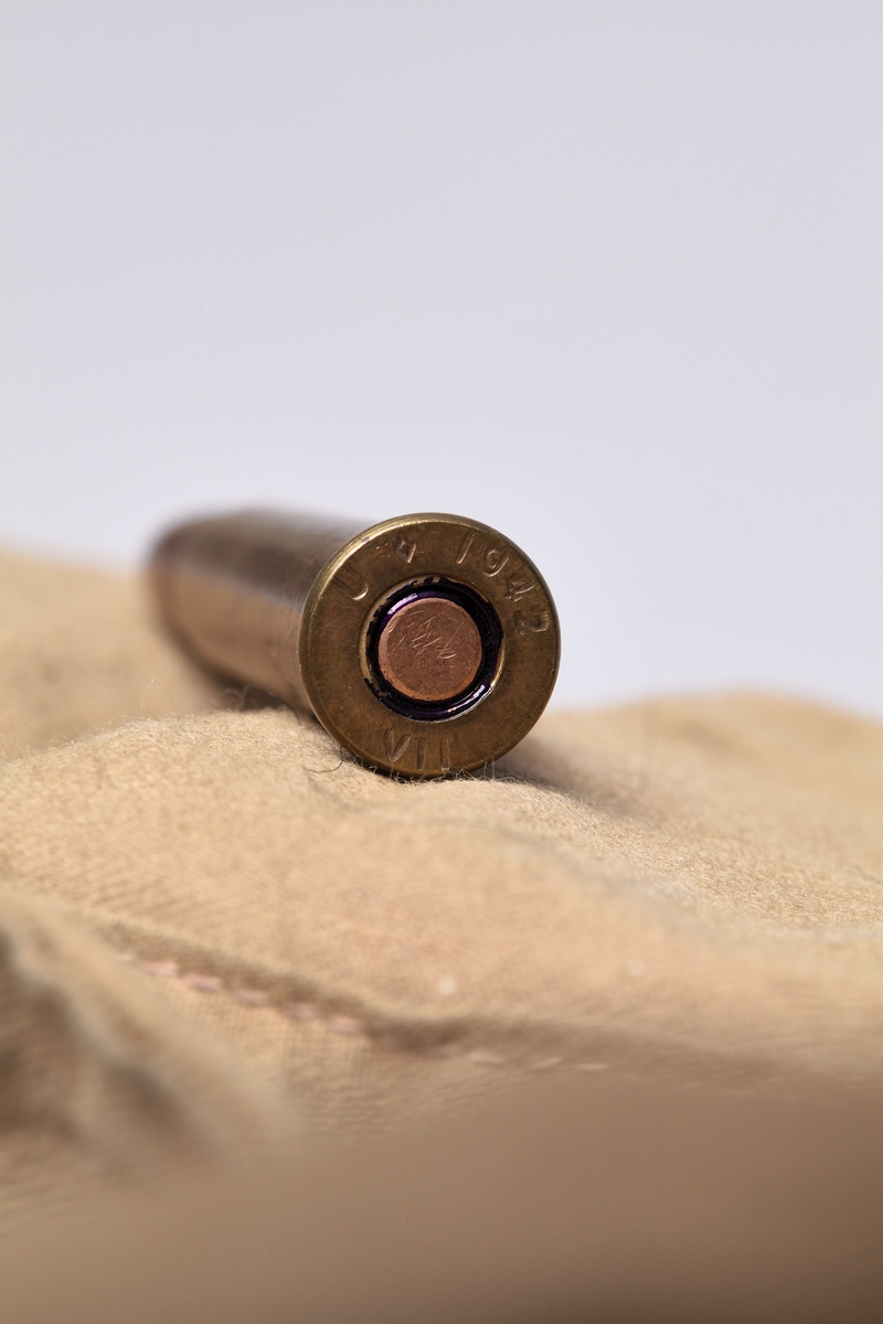 Beltet er rektangulært, laget av bomullstoff og har rom for patroner og rem for å ha rundt livet, eller over skuldra. Skarpladde patroner med helmantelkule. Beltet er oppdelt i 5 rom med klaff over, og en hekte i kobbertråd for hvert rom. Beltet inneholder ca. 50 stk. kragepatroner i kal. 303, helmantel.