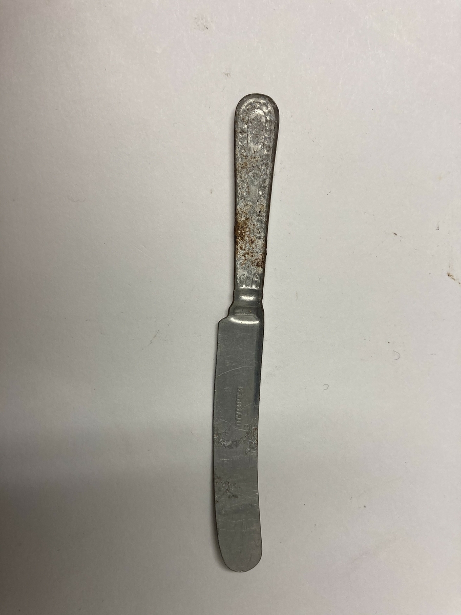 Kniv til bestikk i ni deler til dokkestell. Kniven har en skade. Dokkestell ble gitt til jenter til lek som forberedelse til voksenlivet. 