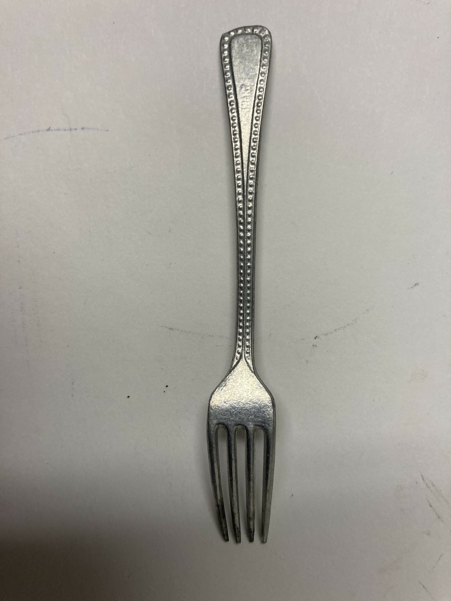 Gaffel til bestikk i ni deler til dokkestell. Dokkestell ble gitt til jenter til lek som forberedelse til voksenlivet. 