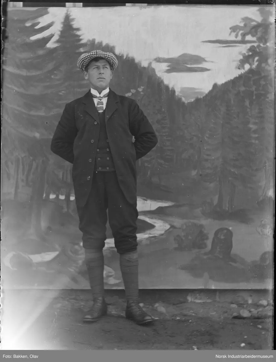 Portrett. Mann i knickers med rutete sixpence foran malt bakgrunn.