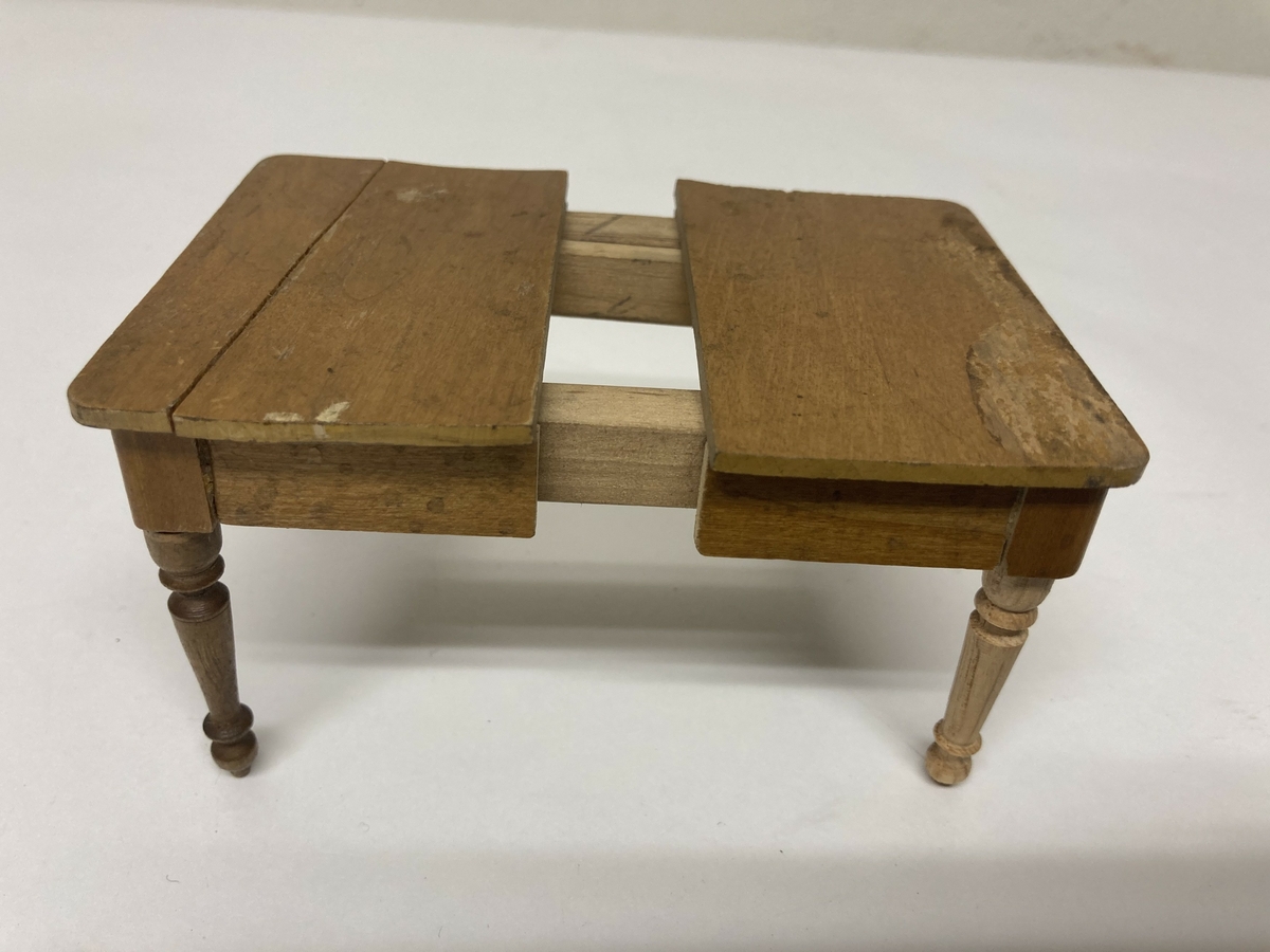 Uttrekkbart spisestuebord til dokkestell. Dokkestell ble gitt til jenter til lek som forberedelse til voksenlivet. 