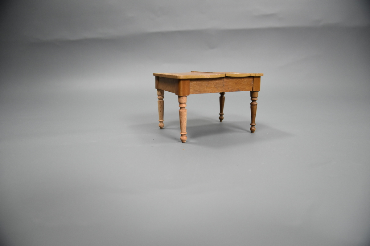 Uttrekkbart spisestuebord til dokkestell. Dokkestell ble gitt til jenter til lek som forberedelse til voksenlivet. 