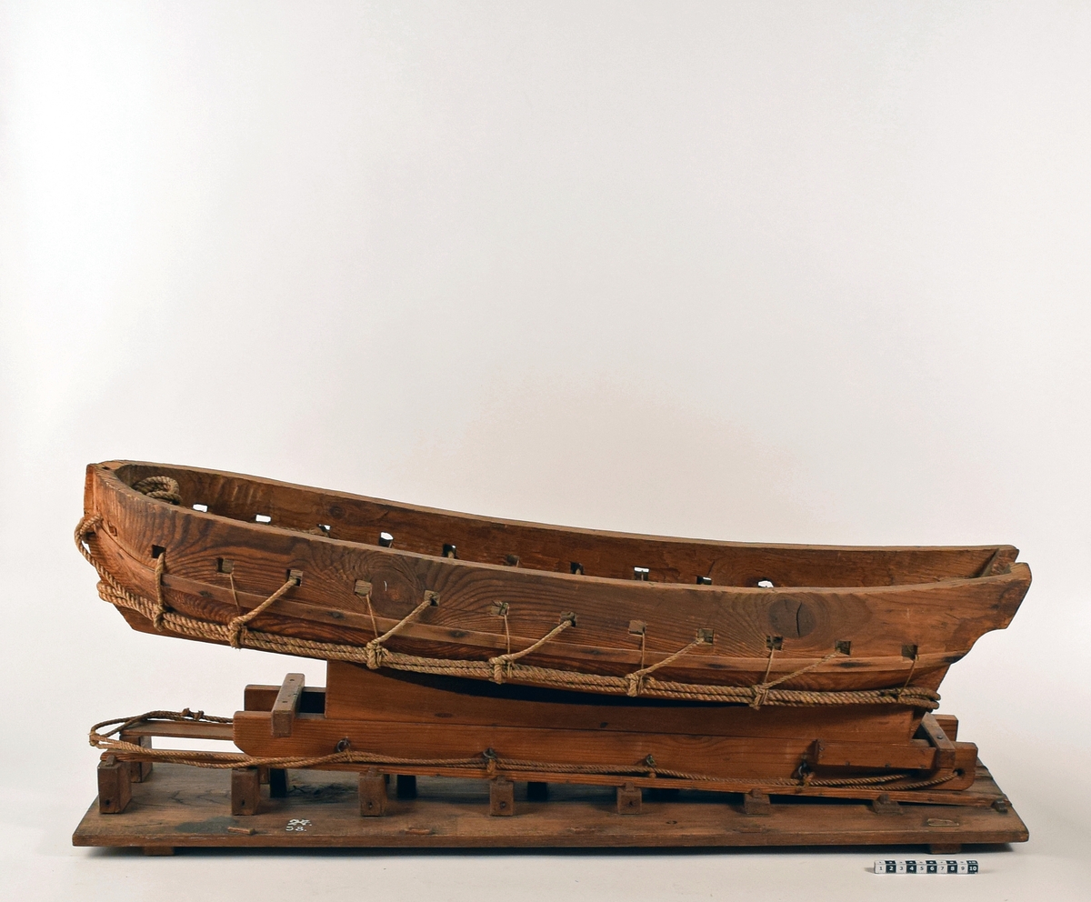 Modell av ett fartyg stående på en upphalningssläde som i sin tur står på en slip. Fartyget består av ett grovt utformat skrov uthugget ur ett trästycke, med kanonportar.
Upphalningssläden, som också är grovt utformad, passar inte till skrovet. Både skrov och släde är försett med olika former av linor och trossar för att användas vid upphalning på en slip. Modellen är omålad.

Löa (mm): 970Modellens dimensioner (mm):  L 955  B 290   H 340
