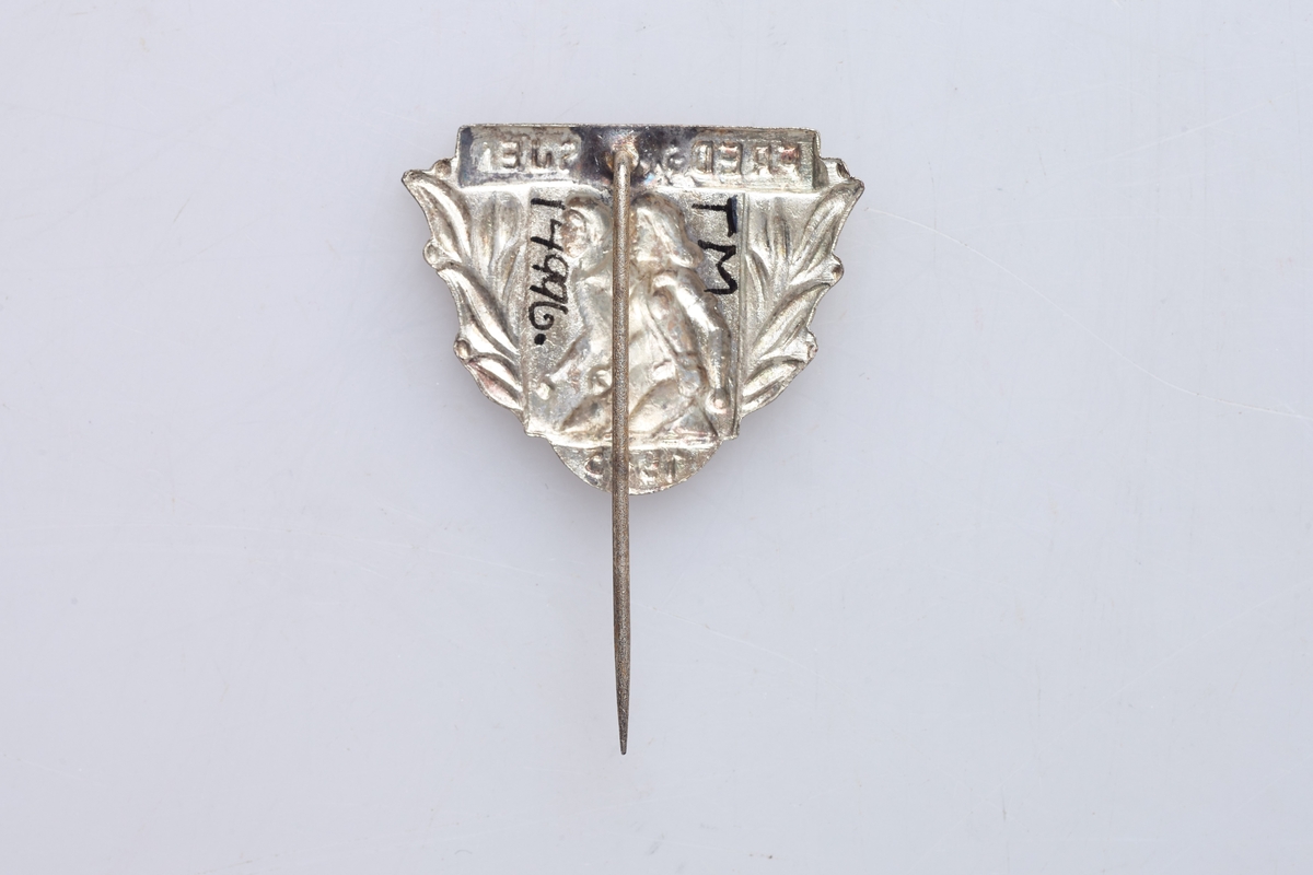 Nål for deltakelse i fredsmarsjen 1945. Nålen viser to personer som går. Støpt merke med påloddet nål.