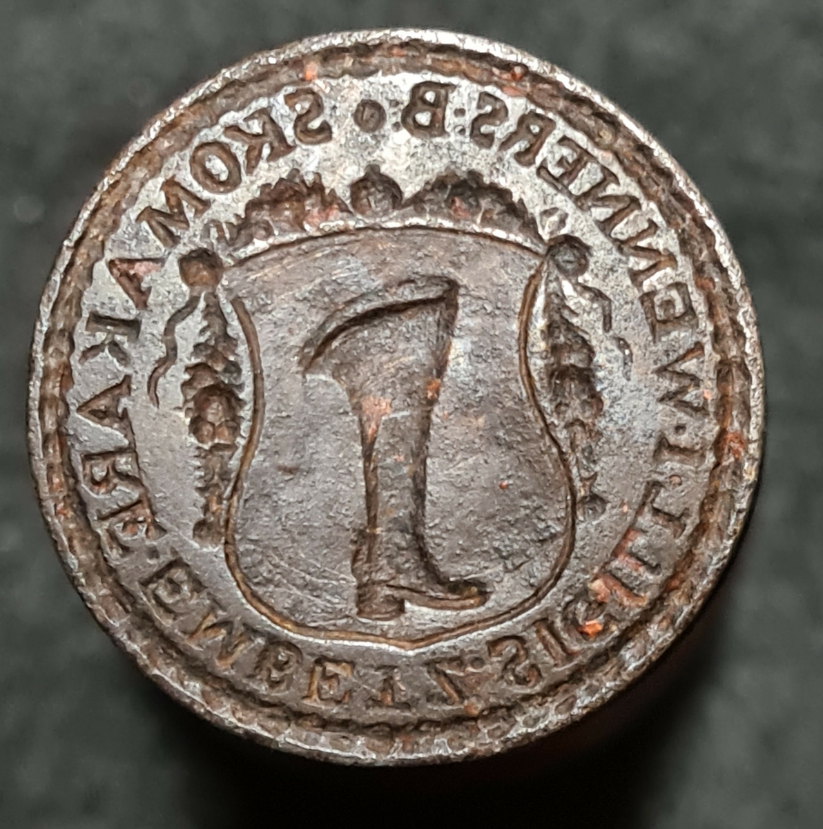 Sigillstamp. Motiv: Stövel och texten: Skomakarämbetets sigill Wenersborg.
Sigillet har tillhört skomakarämbetes skrå som startade 1745 i Vänersborg.