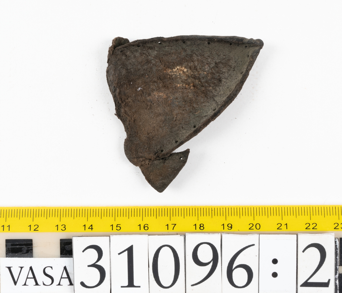 Fyra delar från en tumvante.
Vanten är skuren i två stycken, ett fram- och ett bakstycke, som varit sammanfogat med stygn.
Ett framstycke till en tumvante, fyndnummer 31096. Runt ytterkanterna löper stygnshål. Lädrets kött- och narvsida har släppt från varandra. Vanten har fläckvist rostliknande beläggningar. Lädret är tunt och sprött.
En vanttumme, fyndnummer 31096:1 Längs med ena sidan på vanttummen löper långsmala hål eller öppningar, två och två. Hålen kan härröra från en förstärkning som suttit fästad på vanttummen.
Triangelformat bakstycke till vanttumme, fyndnummer 31096:2. Lädret har skurits ut från vantens bakstycke. Stygnshål är synliga längs med två av sidorna.
Rektangulärt läderstycke, fyndnummer 31096:3. Längs med ytterkanterna löper srygnshål. Lädret är mjukt och narvytan tydlig. Lädret har börjat att spalta sig samt är försett med några rostliknande fläckar. Troligtvis har läderbiten fungerat som en förstärkning och suttit fästad på vantens in - eller utsida.